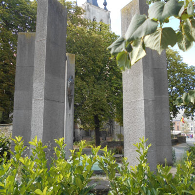 Tienen - Het oorlogsmonument te Tienen herdenkt de militaire en de burgerlijke slachtoffers van de Belgische Onafhankelijkheid (1830) en de Eerste en de Tweede Wereldoorlog. Opschrift op de gedenkmuur: "VOOR UW VRIJHEID ZIJN MENSEN GESTORVEN". Rond de koepel liggen vier stenen met de namen van de kampen "DACHAU", "ZWICKAU", "STALAG IA" en "BREENDONK", plaatsen waarvan grond in urnen naar Tienen werd gebracht. De bronzen figuren op de pijlers verbeelden een weerstander, een soldaat met in de handen een gedenkplaat met opschrift "PRO PATRIA", een politieke gevangene, een weggevoerde en een vrouw met een dood kind in de armen, symbool voor de burgerlijke slachtoffers.